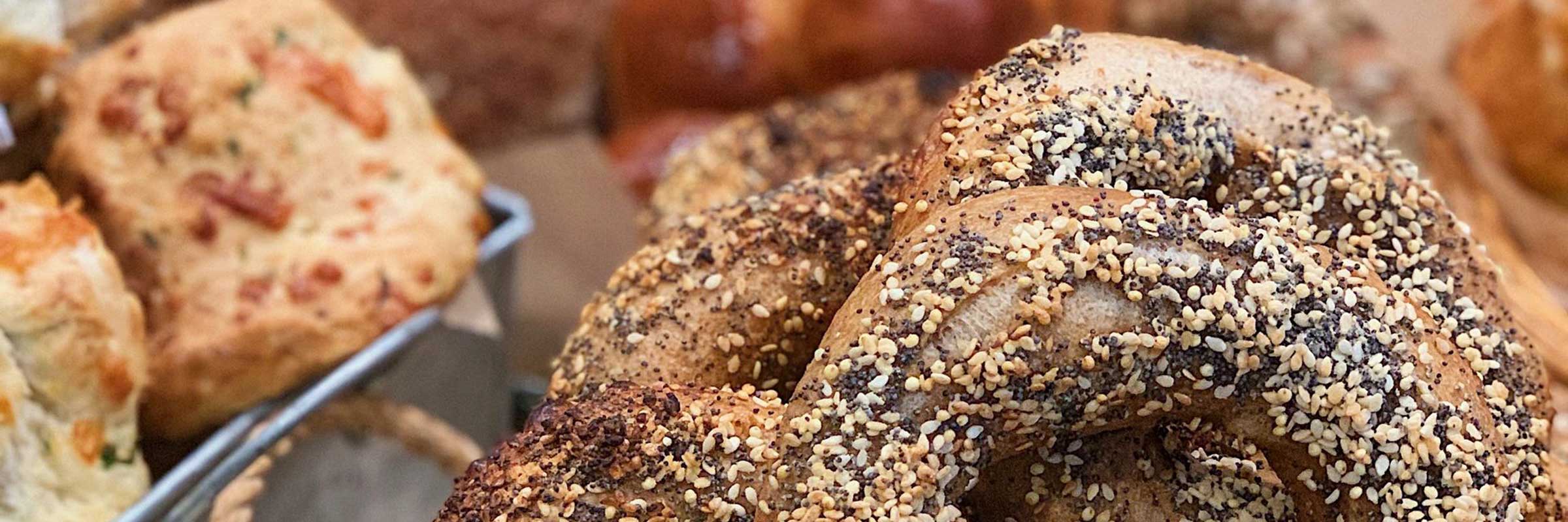 Everything bagels surrounded by other bread items