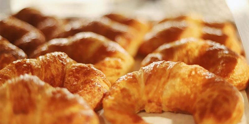 Croissant pastries lined up on a baking tray