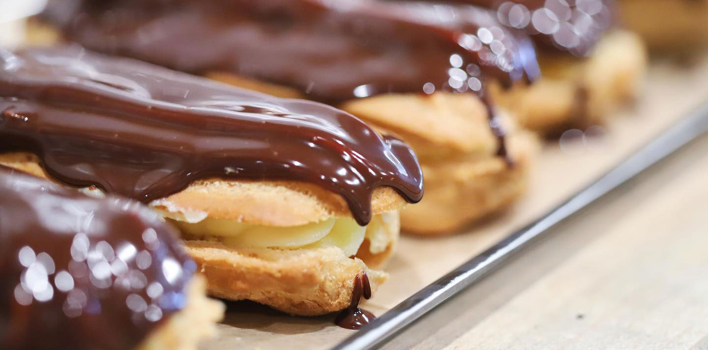 Row of chocolate eclairs still dripping with wet chocolate